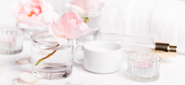 Toalla de spa blanca con rosas y velas sobre fondo blanco.