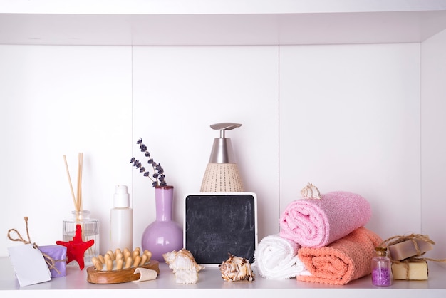 Foto toallas en una bandeja de madera con palillos aromáticos, velas, conchas, masajes de baño.