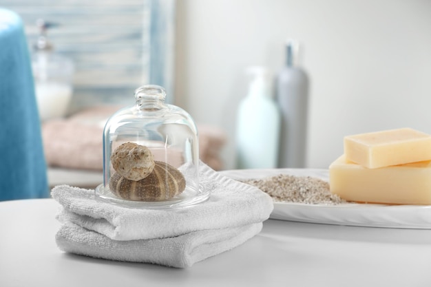 Toallas blancas con conchas en la mesa del baño.