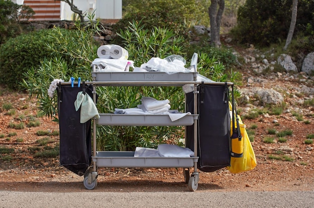 Toallas blancas y productos de limpieza apilados en el carrito del servicio de habitaciones en el complejo hotelero