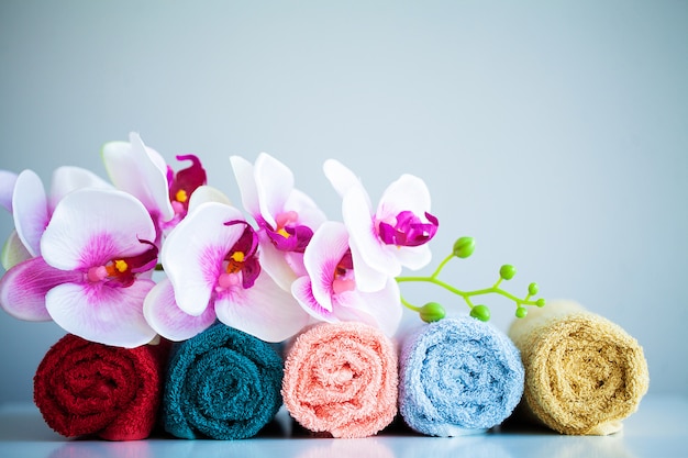 Toallas de colores y orquídeas en mesa blanca con espacio de copia en el baño.