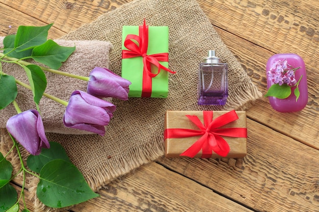 Toallas regalos perfume y flores lilas sobre fondo de madera