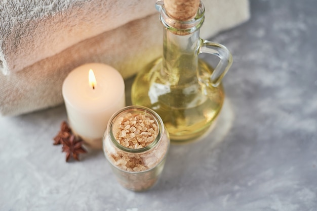 Toallas, velas y aceite de masaje en mesa blanca.