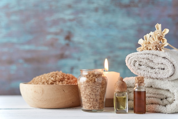 Toallas, velas y aceite de masaje en mesa blanca