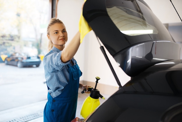 Toallitas lavadoras femeninas en spray de cera, servicio de lavado de autos. Mujer lava vehículos, estación de lavado de autos, negocio de lavado de autos