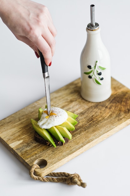 Toast, Avacadosandwich und poschiertes Ei auf einem hölzernen hackenden Brett.