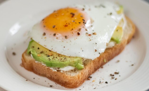 Foto toast mit avocado auf einem weißen teller aus vollkornbrot-spiegeleiern