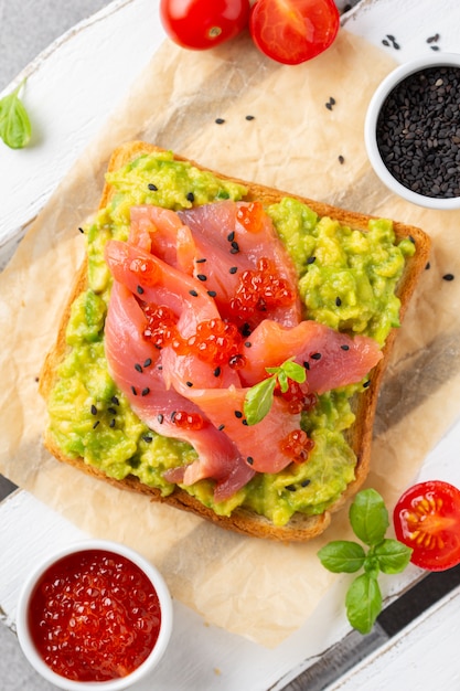 Toast mit Avocado, rotem Fischkaviar und schwarzem Sesam