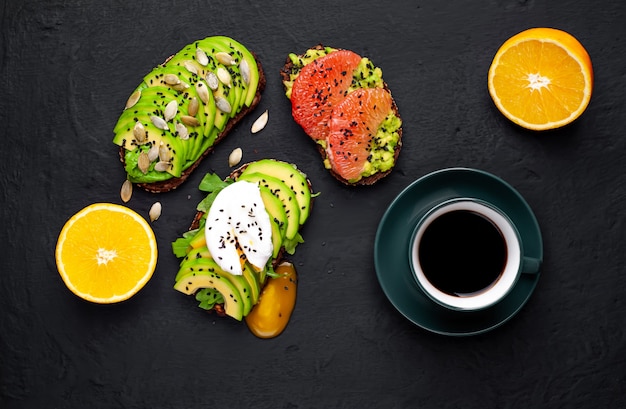 Toast mit Avocado, Sesam, Grapefruit, Orange, Ei und Kaffee auf einem Steinhintergrund. leckeres Frühstück mit Kaffee und Toast