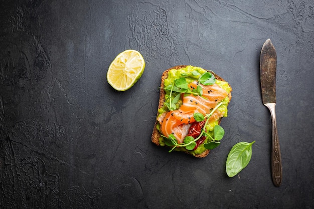 Toast mit Avocadocreme und geräuchertem Lachs über Draufsicht des schwarzen Hintergrundes