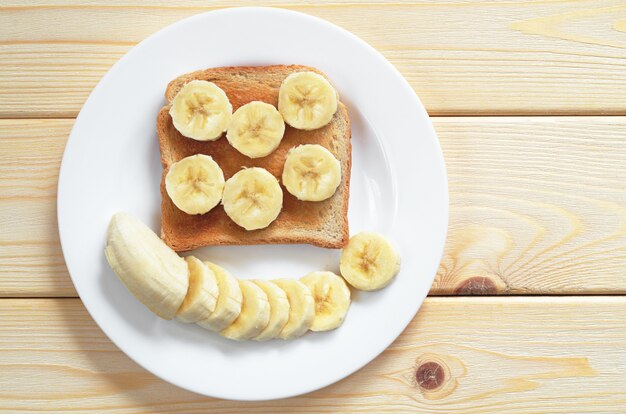 Toast mit Bananen in Teller zum Frühstück auf dem Holztisch