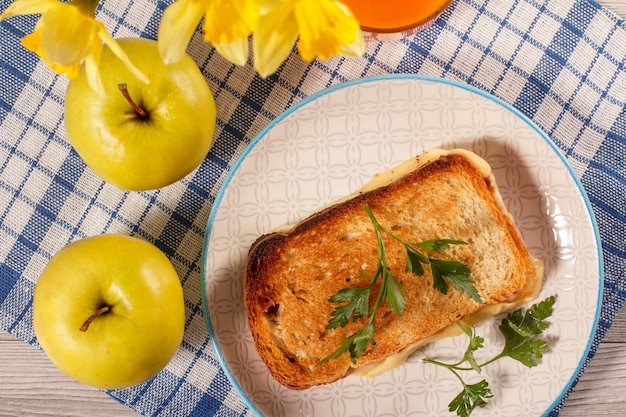 Toast mit Butter und Käse zwei Äpfel Strauß gelber Narzissen und Glas Orangensaft