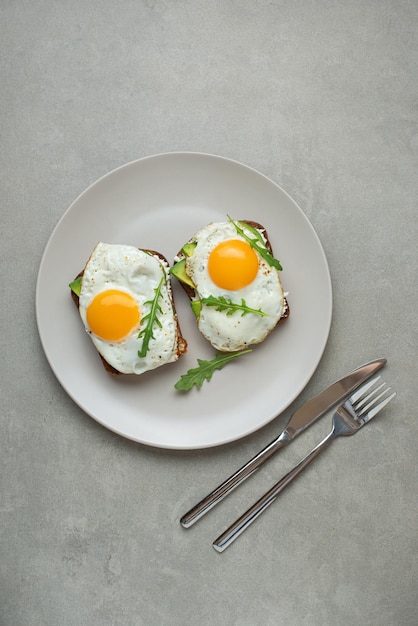 Toast mit Ei und Avocado auf grauem Hintergrund in einem gesunden Frühstück auf dem Teller