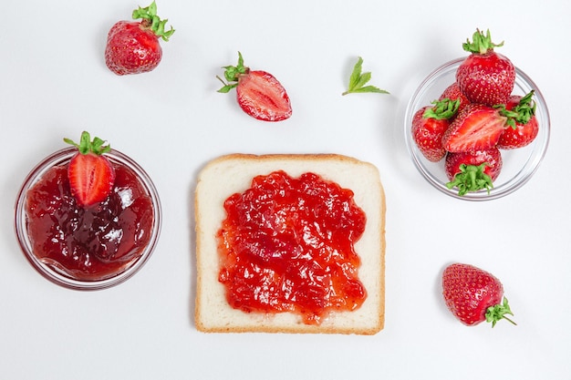 Toast mit Erdbeermarmelade zum Frühstück auf weißem rustikalem Holzhintergrund Draufsicht