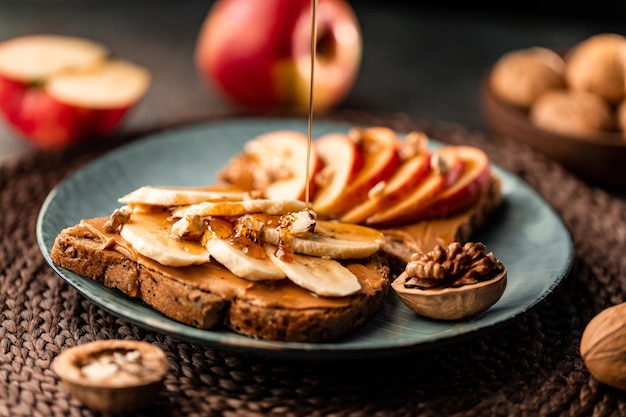 Toast mit Erdnussbutter, Apfel, Banane, Walnuss und Honig Gesundes vegetarisches Frühstückskonzept