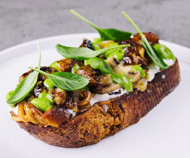 Toast mit gebratenen Steinpilzen auf weißer Platte