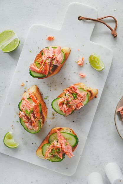 Toast mit geräuchertem Lachs und frischer Gurke, serviert mit Limettenspänen