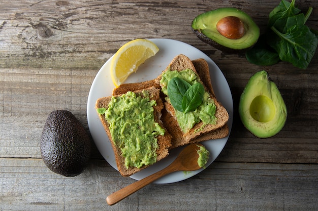 Toast mit Guacamole, Avocadoscheiben. Gesundes Essen, Snack. Frühstück. Rustikaler Holztisch.