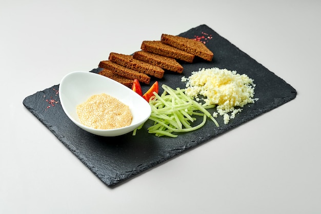 Toast mit Käse und Hechtkaviar auf einem Schieferbrett auf grauem Hintergrund