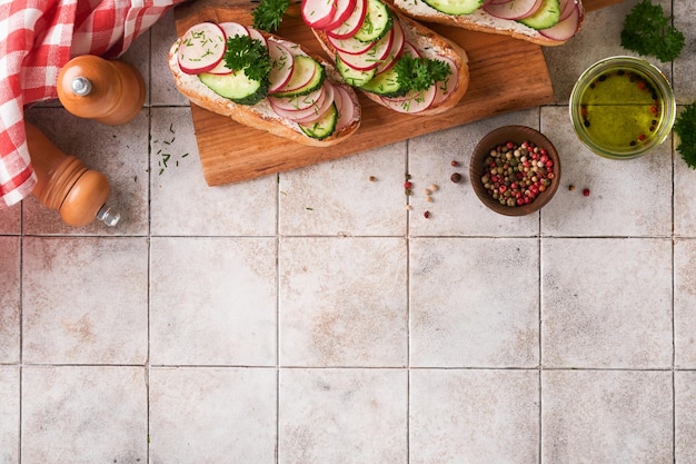 Toast mit Käse und Rettich Sandwiches mit Hüttenkäse, Rettich, Gurke und Frühlingszwiebeln auf altem, rissigem Fliesenhintergrund Gesunde Frühlingssandwiches Traditioneller skandinavischer Toast Draufsicht