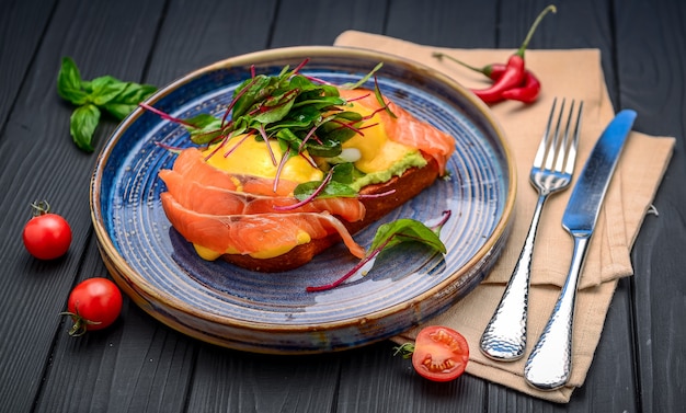 Toast mit Lachs, pochiertem Ei und Avocado auf einem Teller. Frühstück im Restaurant