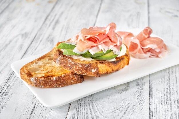 Toast mit Scheiben Avocado, Schinken und Frischkäse