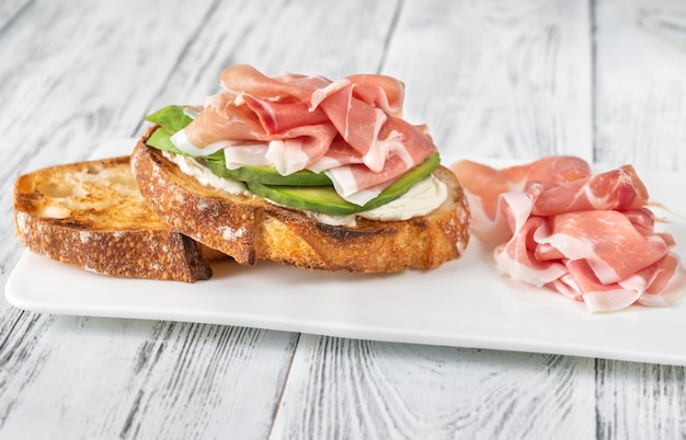 Toast mit Scheiben Avocado, Schinken und Frischkäse