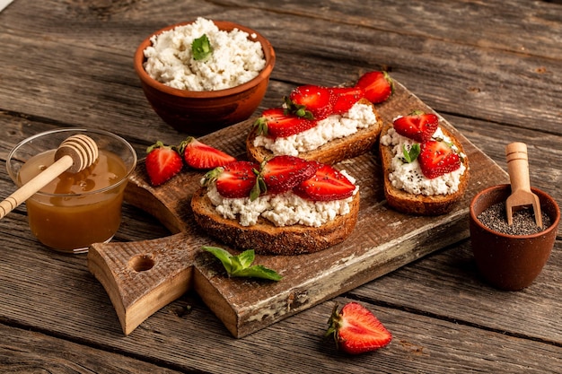 Toast oder Bruschetta mit Erdbeere und Minze auf Frischkäse-Ricotta Köstliches Frühstück oder Snack-Draufsicht