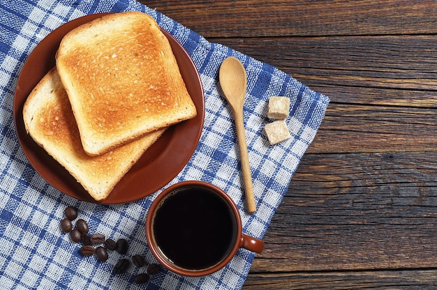 Toast und eine Tasse schwarzen Kaffee auf dunklem Holztisch