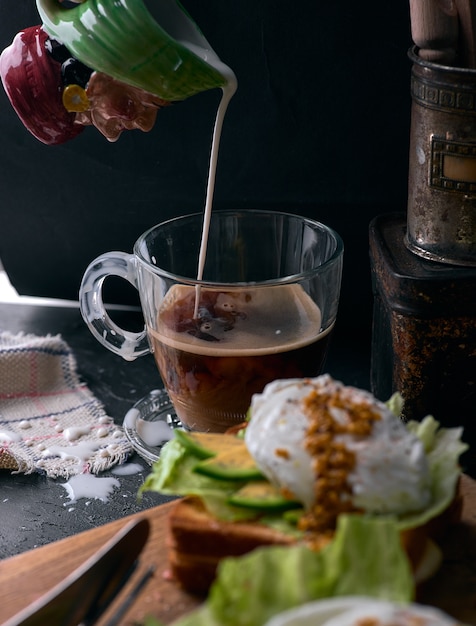 Toastbrot mit geschnittener Avocado, Eierbeutel und Gemüse auf Holzschneidebrett.