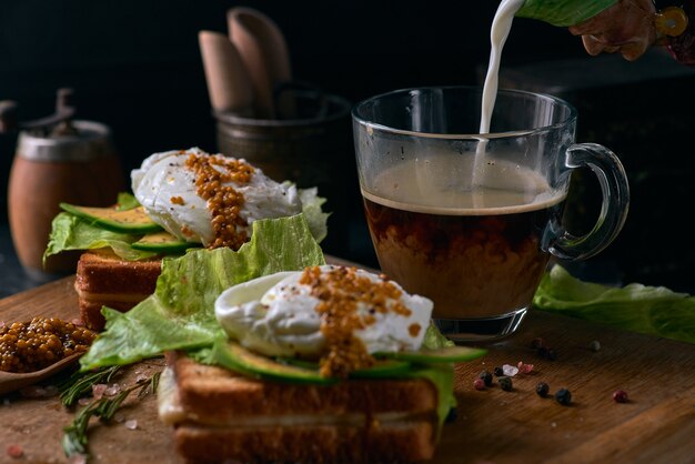 Toastbrot mit geschnittener Avocado, Eierbeutel und Gemüse auf Holzschneidebrett.