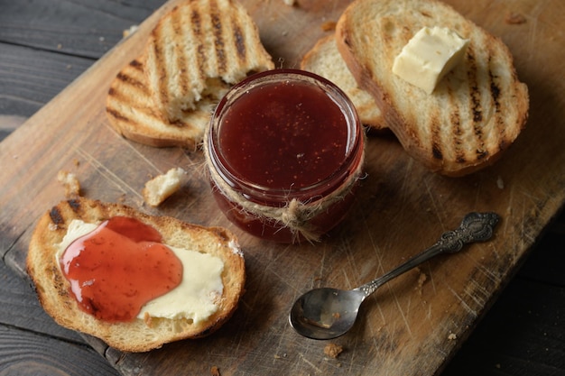 Toastbrot mit hausgemachter Erdbeermarmelade und auf rustikalem Tisch mit Butter zum Frühstück oder Brunch