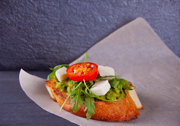 Toastbrot mit tomaten, feta und rucola auf dem papier