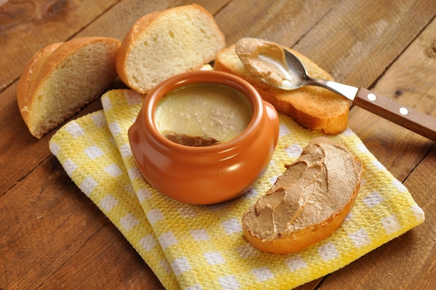 Toastbrot und ein Keramiktopf mit Pastete auf hölzernem Hintergrund