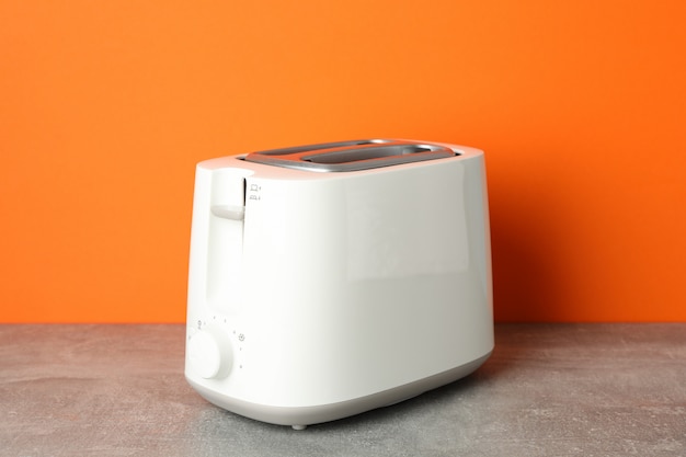 Toaster auf grauem Tisch gegen orange Hintergrund, Platz für Text