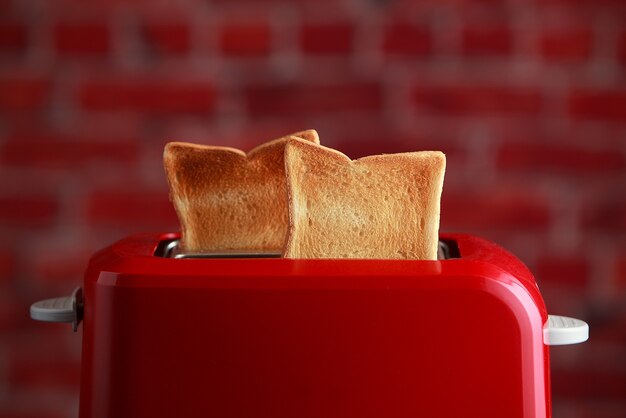 Toaster mit geröstetem geschnittenem Brot auf Ziegelsteinwandhintergrund. Küchenausstattung