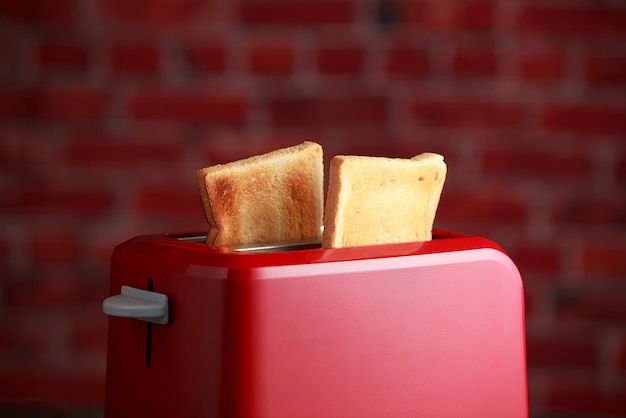 Toaster mit geröstetem geschnittenem Brot auf Ziegelsteinwandhintergrund. Küchenausstattung