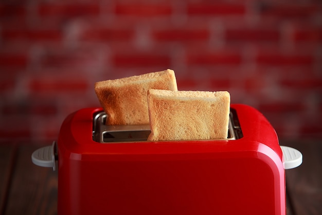 Toaster mit geröstetem geschnittenem Brot auf Ziegelsteinwandhintergrund. Küchenausstattung