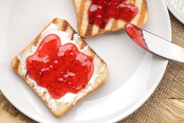 Toasts mit Marmelade gebratener knuspriger Toast mit roter Marmelade auf einem natürlichen Holztischfrühstück von oben