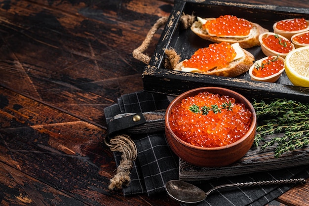 Toasts und Törtchen mit rotem Kaviar und Butter im Holztablett. Hölzerner Hintergrund. Ansicht von oben. Platz kopieren.