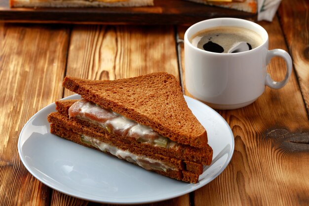 Toastsandwich und Tasse Kaffee auf Serviette auf Holztisch