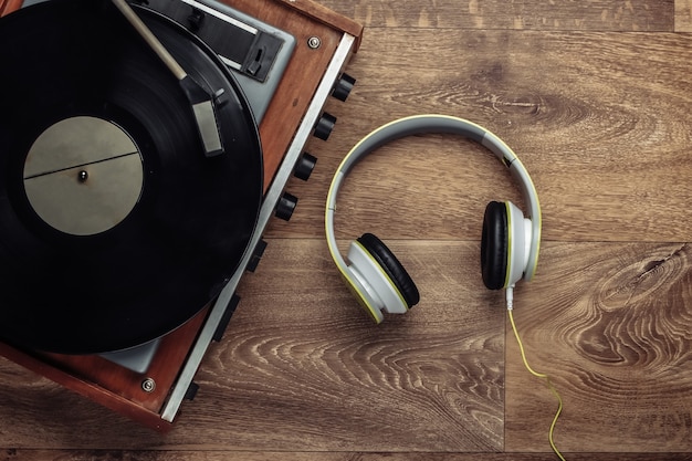 Tocadiscos de vinilo retro con auriculares estéreo en un piso de madera