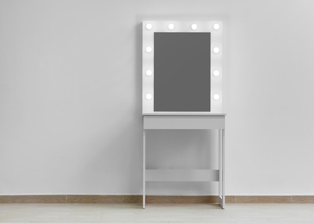 Tocador de maquillaje blanco moderno con espejo y retroiluminación en un primer plano de la pared blanca