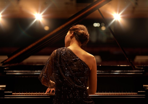 Tocando para la audiencia Toma de una mujer joven tocando el piano durante un concierto musical