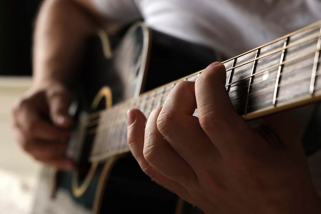 Tocando violão Dedilhando violão Músico toca música Dedos de homem segurando mediador Mão de homem tocando braço de violão em quarto escuro Pessoa irreconhecível ensaiando closeup do braço da guitarra