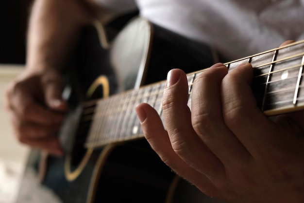 Tocando violão Dedilhando violão Músico toca música Dedos de homem segurando mediador Mão de homem tocando braço de violão em quarto escuro Pessoa irreconhecível ensaiando closeup do braço da guitarra