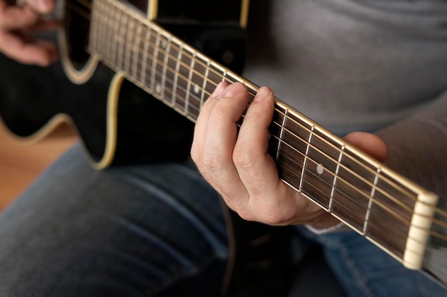 Tocando violão Dedilhando violão preto Músico toca música Dedos de homem segurando mediador Mão masculina tocando pescoço de violão em quarto escuro Pessoa irreconhecível ensaiando closeup do braço da guitarra