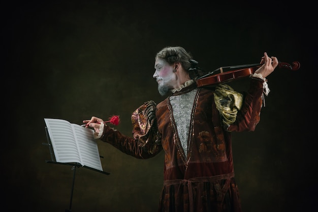 Foto tocando el violín joven como johann bach aislado sobre fondo verde oscuro