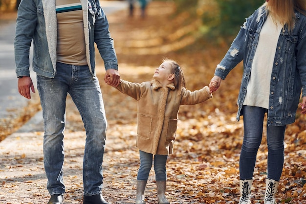 Tochter an den Händen halten Glückliche Familie ist zur Herbstzeit zusammen im Park