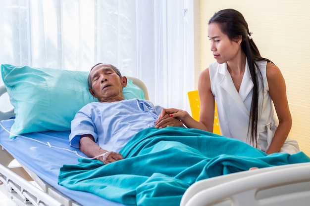 Foto tochter besucht und tröstet älteren mannpatienten im krankenhaus.